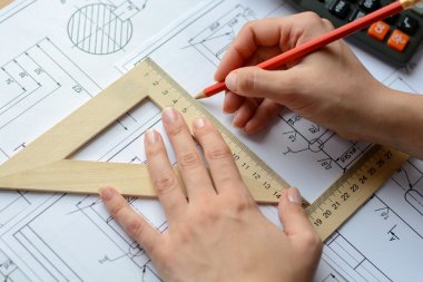 Kız mimar Ofis Masası, kağıt üzerine büyük kalem tarafından bir plan, grafik, tasarım, geometrik şekiller çizer. Yumuşak odak