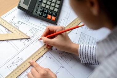 Kız mimar Ofis Masası, kağıt üzerine büyük kalem tarafından bir plan, grafik, tasarım, geometrik şekiller çizer. Yumuşak odak