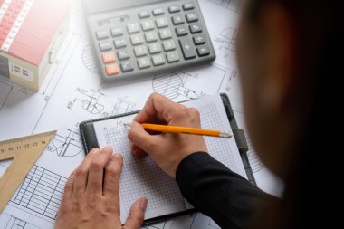 Kız mimar Ofis Masası, kağıt üzerine büyük kalem tarafından bir plan, grafik, tasarım, geometrik şekiller çizer. Yumuşak odak