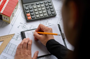 Kız mimar Ofis Masası, kağıt üzerine büyük kalem tarafından bir plan, grafik, tasarım, geometrik şekiller çizer. Yumuşak odak