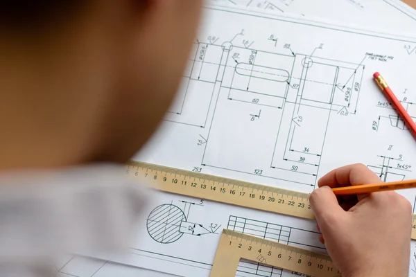 Man architect dibuja un plano, gráfico, diseño, formas geométricas a lápiz en una hoja grande de papel en el escritorio de la oficina. Enfoque suave . — Foto de Stock