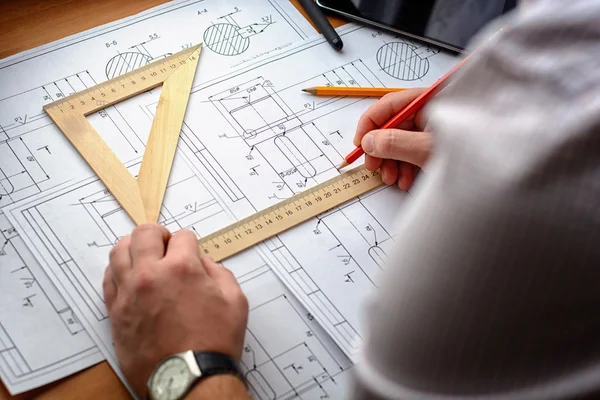 Adam mimar Ofis Masası, kağıt üzerine büyük kalem tarafından bir plan, grafik, tasarım, geometrik şekiller çizer. Yumuşak odak.