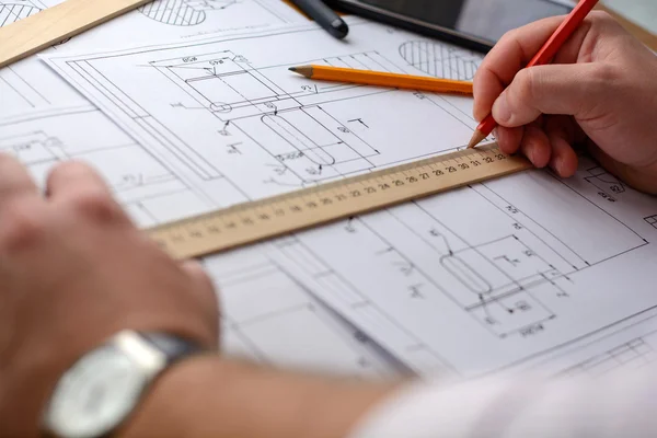 Man architect dibuja un plano, gráfico, diseño, formas geométricas a lápiz en una hoja grande de papel en el escritorio de la oficina. Enfoque suave . — Foto de Stock