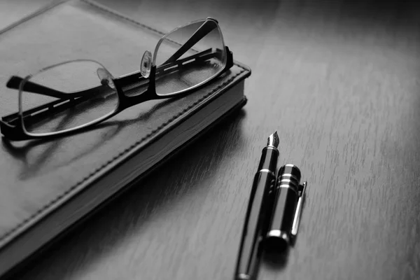 Företag tillbehör på skrivbordet: anteckningsbok, dagbok, reservoarpenna, Glasögon, klocka. Makro med oskärpa och mjukt fokus — Stockfoto