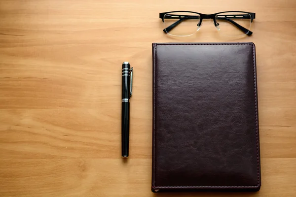 Деловые аксессуары на рабочем столе: ноутбук, дневник, авторучка, очки, часы. Макро с размытым и мягким фокусом — стоковое фото