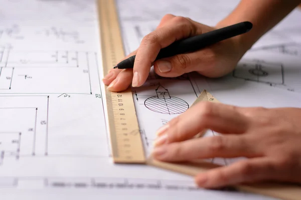 Girl architect dibuja un plano, gráfico, diseño, formas geométricas a lápiz en una gran hoja de papel en el escritorio de la oficina. Enfoque suave — Foto de Stock
