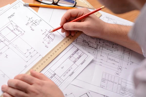 Girl architect dibuja un plano, gráfico, diseño, formas geométricas a lápiz en una gran hoja de papel en el escritorio de la oficina. Enfoque suave — Foto de Stock