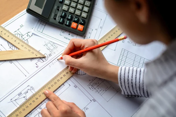 Girl architect dibuja un plano, gráfico, diseño, formas geométricas a lápiz en una gran hoja de papel en el escritorio de la oficina. Enfoque suave — Foto de Stock