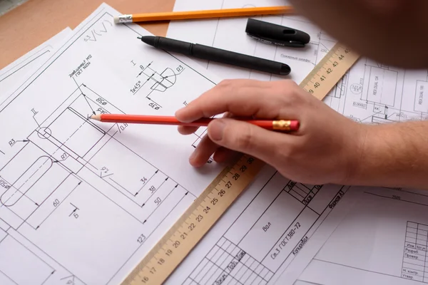 Arsitek gadis menggambar rencana, grafik, desain, bentuk geometris dengan pensil pada selembar kertas besar di meja kantor. Fokus lembut Stok Gambar
