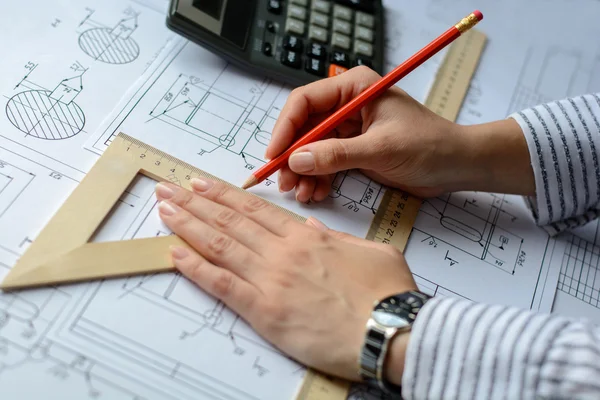 Arsitek gadis menggambar rencana, grafik, desain, bentuk geometris dengan pensil pada selembar kertas besar di meja kantor. Fokus lembut Stok Lukisan  