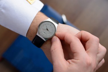 Bir defter, dolma kalem ile ahşap masa saati ile altın kol düğmesi ile Beyaz gömlekli bir adamın elini