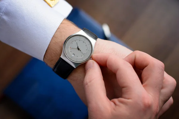 Hand of a man in white shirt with gold cufflinks with clock on a wooden desk with a notebook, fountain pen — Stock Photo, Image