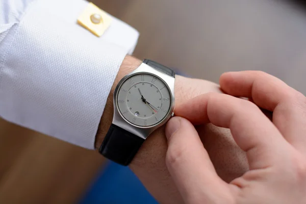 Hand of a man in white shirt with gold cufflinks with clock on a wooden desk with a notebook, fountain pen — Stock Photo, Image