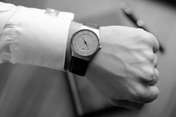 Hand of a man in white shirt with gold cufflinks with clock on a wooden desk with a notebook, fountain pen — Stock Photo, Image