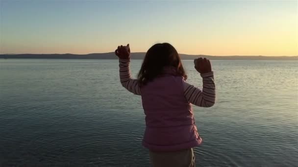 Liten flicka kasta småsten i havet — Stockvideo