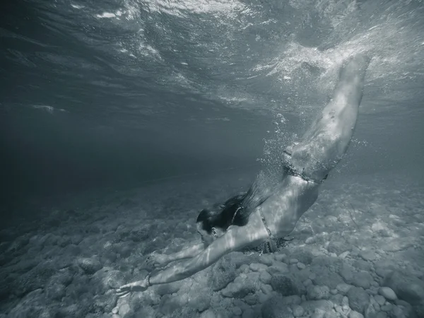 Молодая девушка ныряет в море под водой — стоковое фото