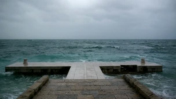 Суровая погода на море и волны, разбивающиеся о каменный пирс — стоковое видео