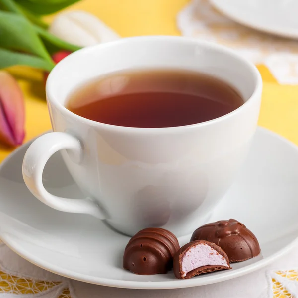 Una taza de té con caramelos de chocolate en forma de huevo de Pascua — Foto de Stock