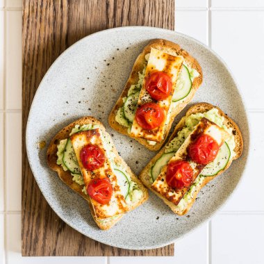 Avokado, kızarmış peynir, taze salatalık ve kızarmış domates tostu, kare şeklinde.