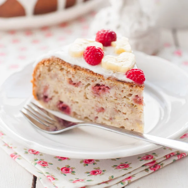 Pastel de plátano con glaseado de azúcar cubierto con frambuesas y plátano —  Fotos de Stock