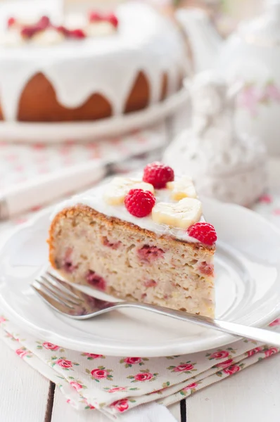 Bananenkuchen mit Zuckerglasur belegt mit Himbeeren und Banane — Stockfoto