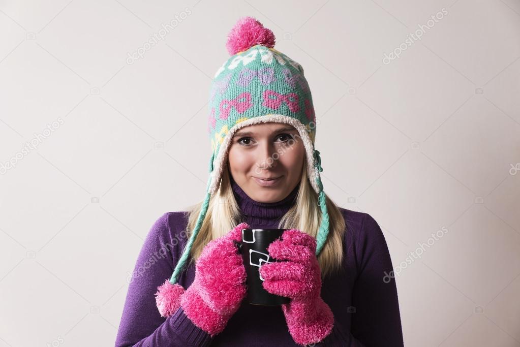 woman wearing a knitted cap holding a cup