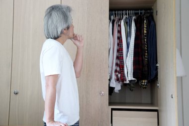 Üst düzey Asyalı adam yatak odasında kıyafet seçiyor..