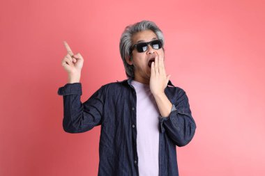 Pembe arka planda duran Asyalı adam..