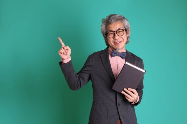 Yeşil arka planda duran kıdemli Asyalı öğretmen..