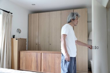 Asyalı kıdemli adam yatak odasının kapısını aç..