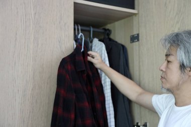Üst düzey Asyalı adam yatak odasında kıyafet seçiyor..