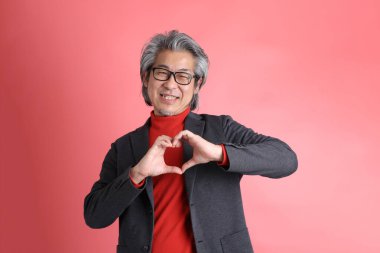 Pembe arka planda duran Asyalı adam..