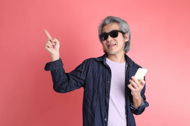 Pembe arka planda duran Asyalı adam..