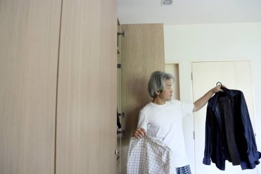 Üst düzey Asyalı adam yatak odasında kıyafet seçiyor..