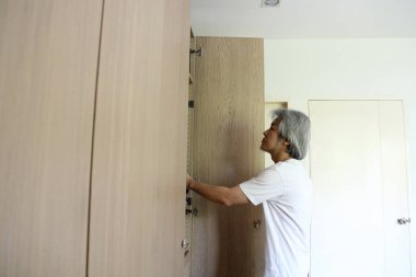 Üst düzey Asyalı adam yatak odasında kıyafet seçiyor..