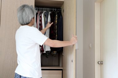 Üst düzey Asyalı adam yatak odasında kıyafet seçiyor..