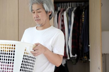 Çamaşır yıkamak için çamaşır sepeti taşıyan Asyalı adam..