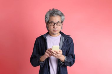 Pembe arka planda duran Asyalı adam..