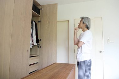 Üst düzey Asyalı adam yatak odasında kıyafet seçiyor..