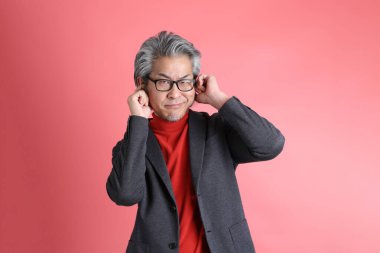 Pembe arka planda duran Asyalı adam..