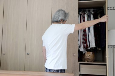 Üst düzey Asyalı adam yatak odasında kıyafet seçiyor..