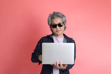 Pembe arka planda duran Asyalı adam..