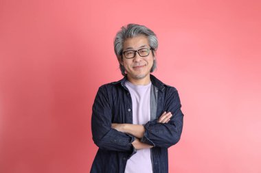 Pembe arka planda duran Asyalı adam..