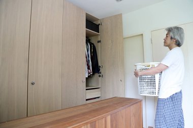 Çamaşır yıkamak için çamaşır sepeti taşıyan Asyalı adam..