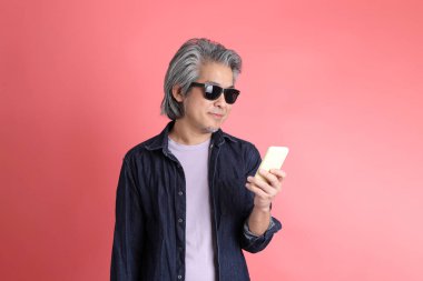 Pembe arka planda duran Asyalı adam..