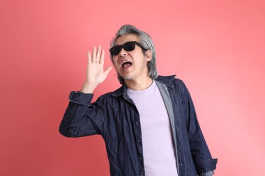 Pembe arka planda duran Asyalı adam..