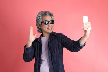 Pembe arka planda duran Asyalı adam..