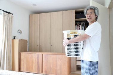 Çamaşır yıkamak için çamaşır sepeti taşıyan Asyalı adam..