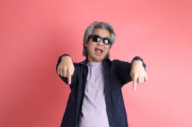 Pembe arka planda duran Asyalı adam..