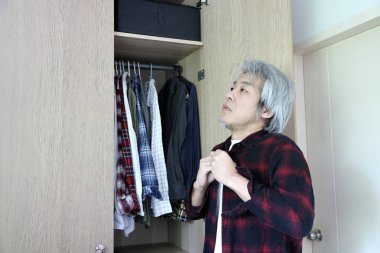 Üst düzey Asyalı adam yatak odasında kıyafet seçiyor..